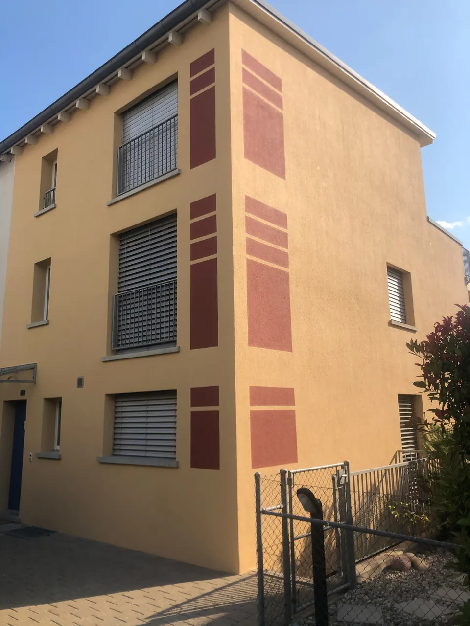 Fassade in Ocker mit roten Farbakzenten