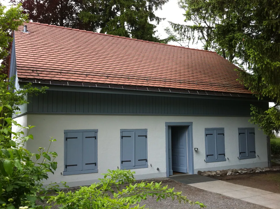Wohnhaus mit weisser Fassade und grauen Fensterläden