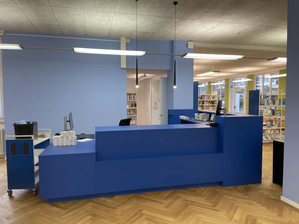 Bibliothek mit blauem Empfangsbereich und hellblauen Wänden