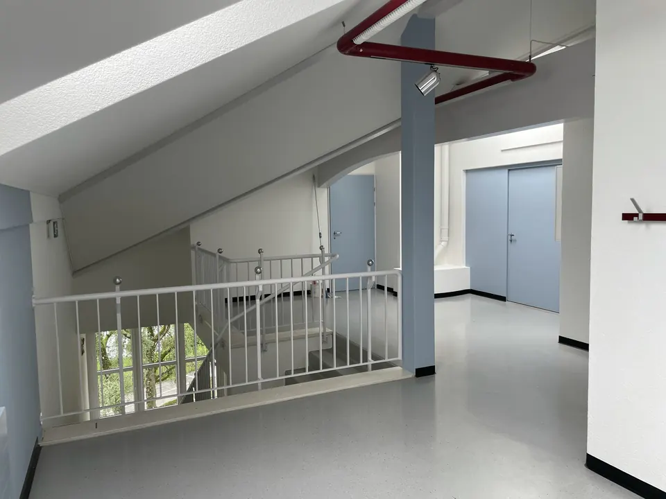 Treppenhaus mit weissen Wänden und hellgrauen Türen